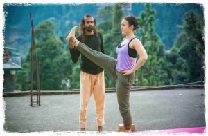 yoga teacher is correcting his student