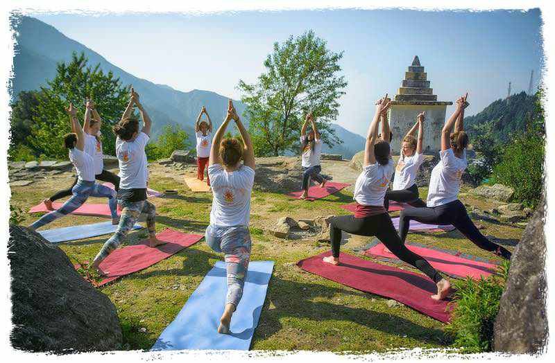 yoga teacher is aligning student in warrior pose