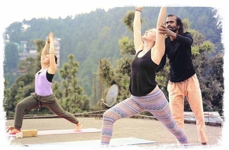 yoga teacher is aligning studend in warrior pose